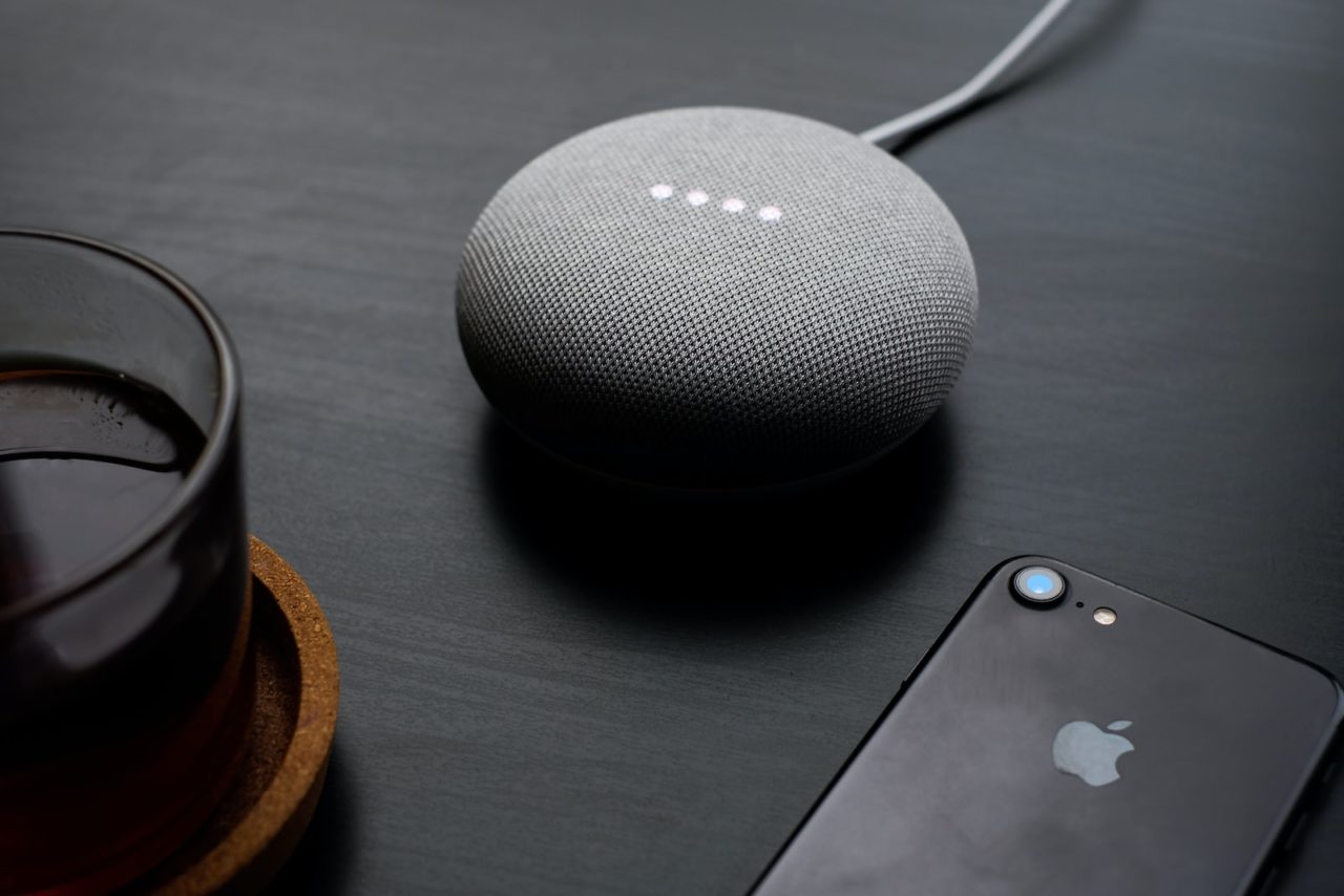 turned-on round gray Google Bluetooth speaker